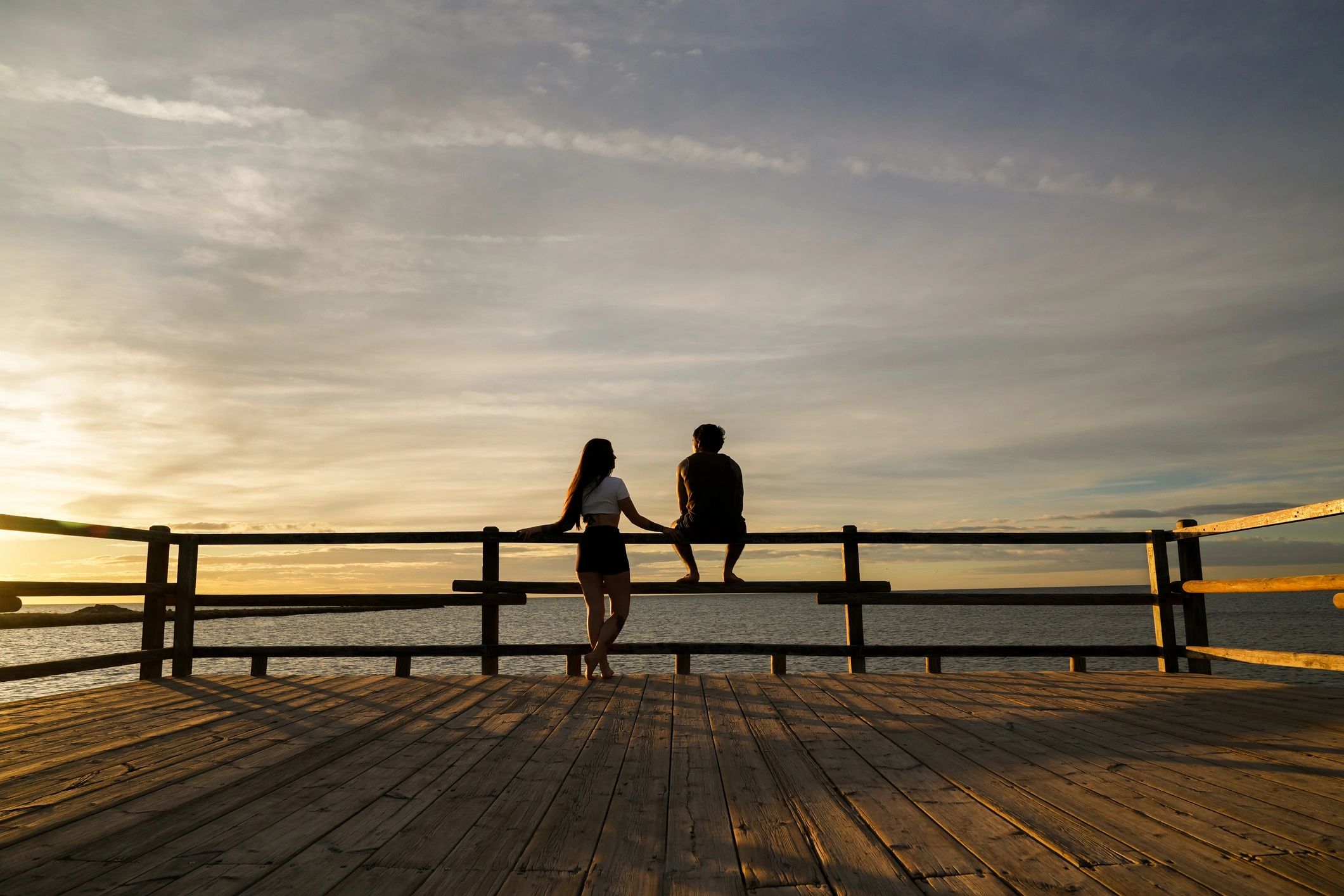 Couple holding hands watching sunset from pier